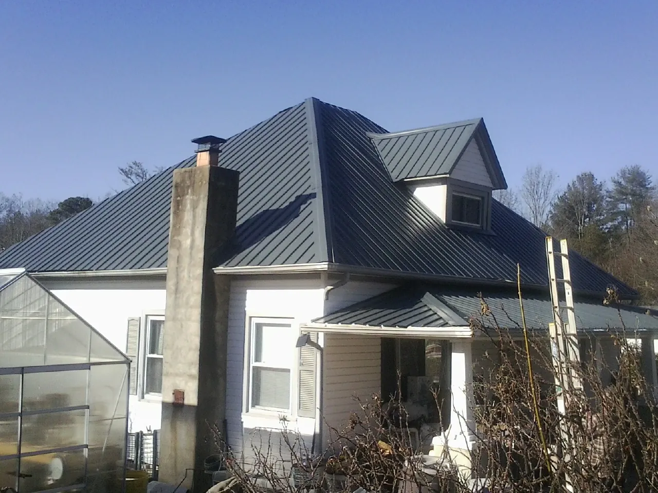Dark blue standing seam metal roof on a white farmhouse with dormer — Slate & Tile Roof Repair by Roofing Brothers in Duvall