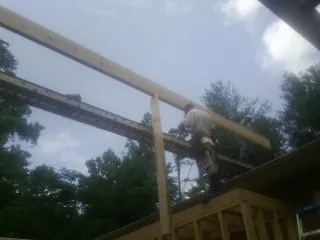 Carpenter setting a ridge beam over a new addition frame — Ice Dam Removal by Roofing Brothers in Duvall