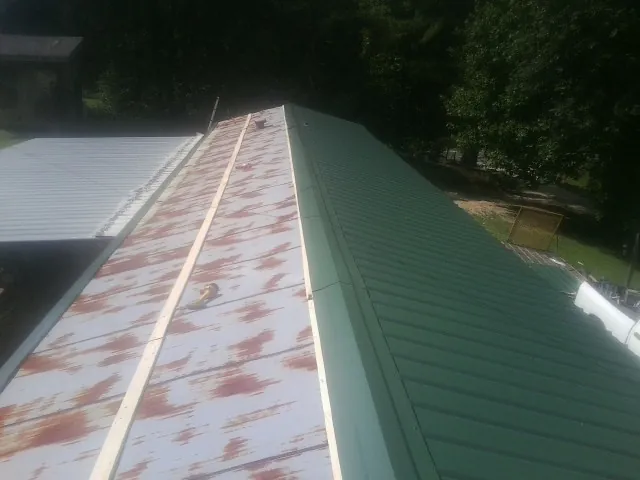 Old rusted panels beside newly installed green metal roofing — Wind Damage Roof Repair by Roofing Brothers in Duvall
