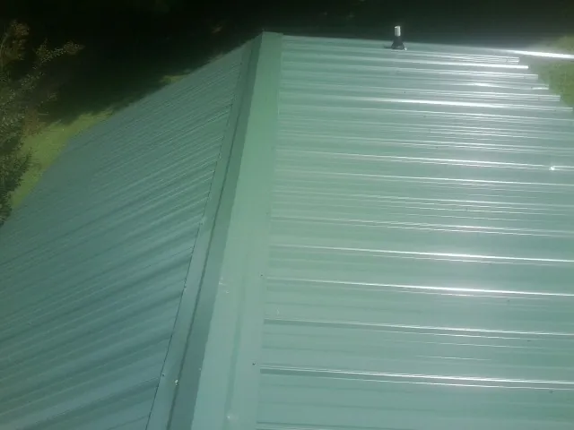 New green metal panels meeting at the ridge of a roof — Flat Roof Repair work by our crew in Duvall