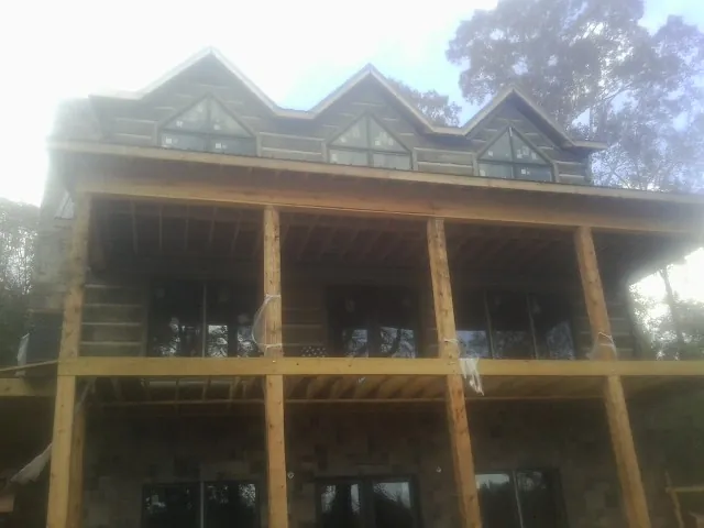 Dormers and porch framing on a large log home under construction — Roof Coating work by our crew in Duvall