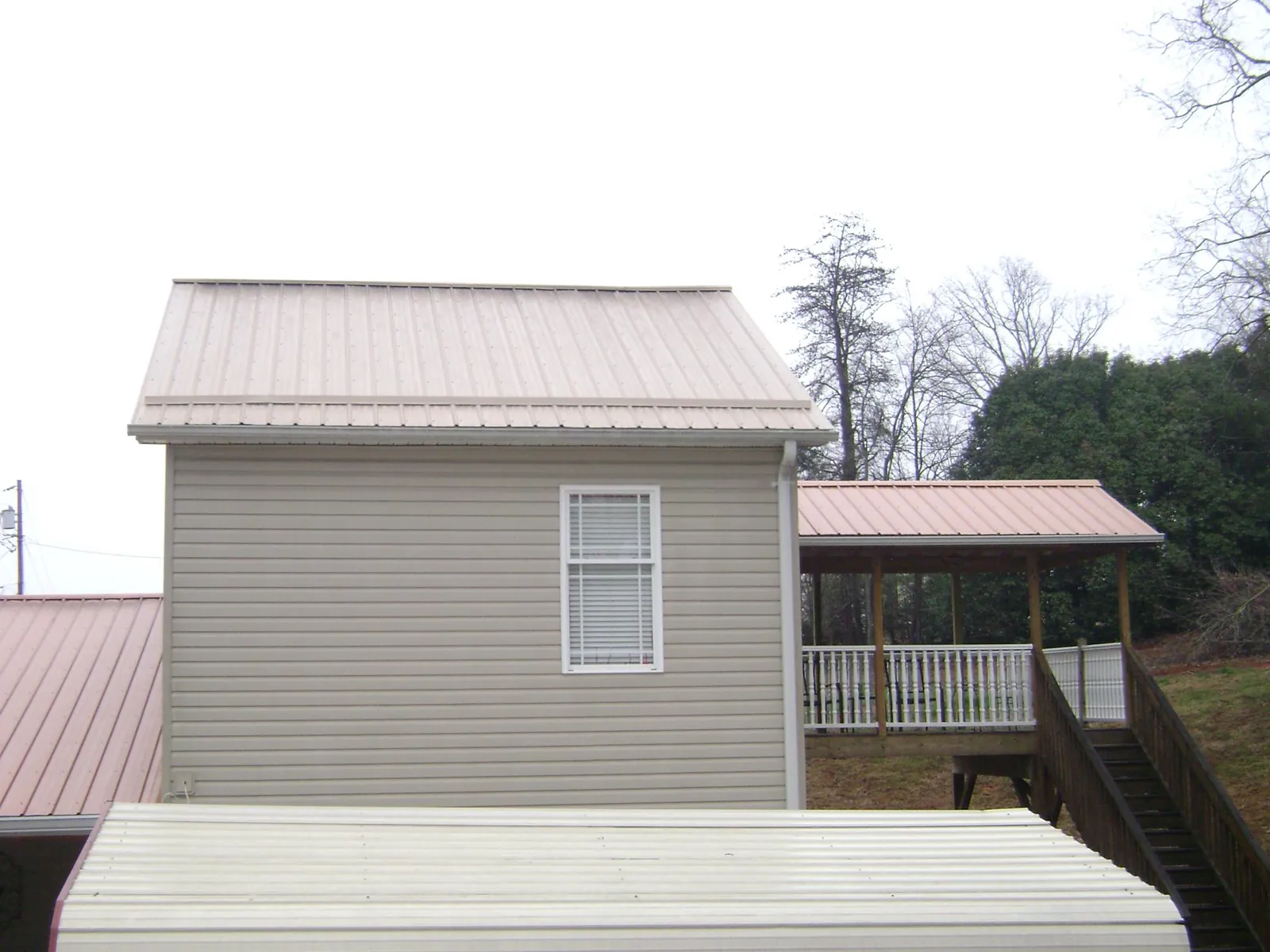 Tan metal roofs on a two story addition and attached porch, from a Roof Replacement job in Duvall