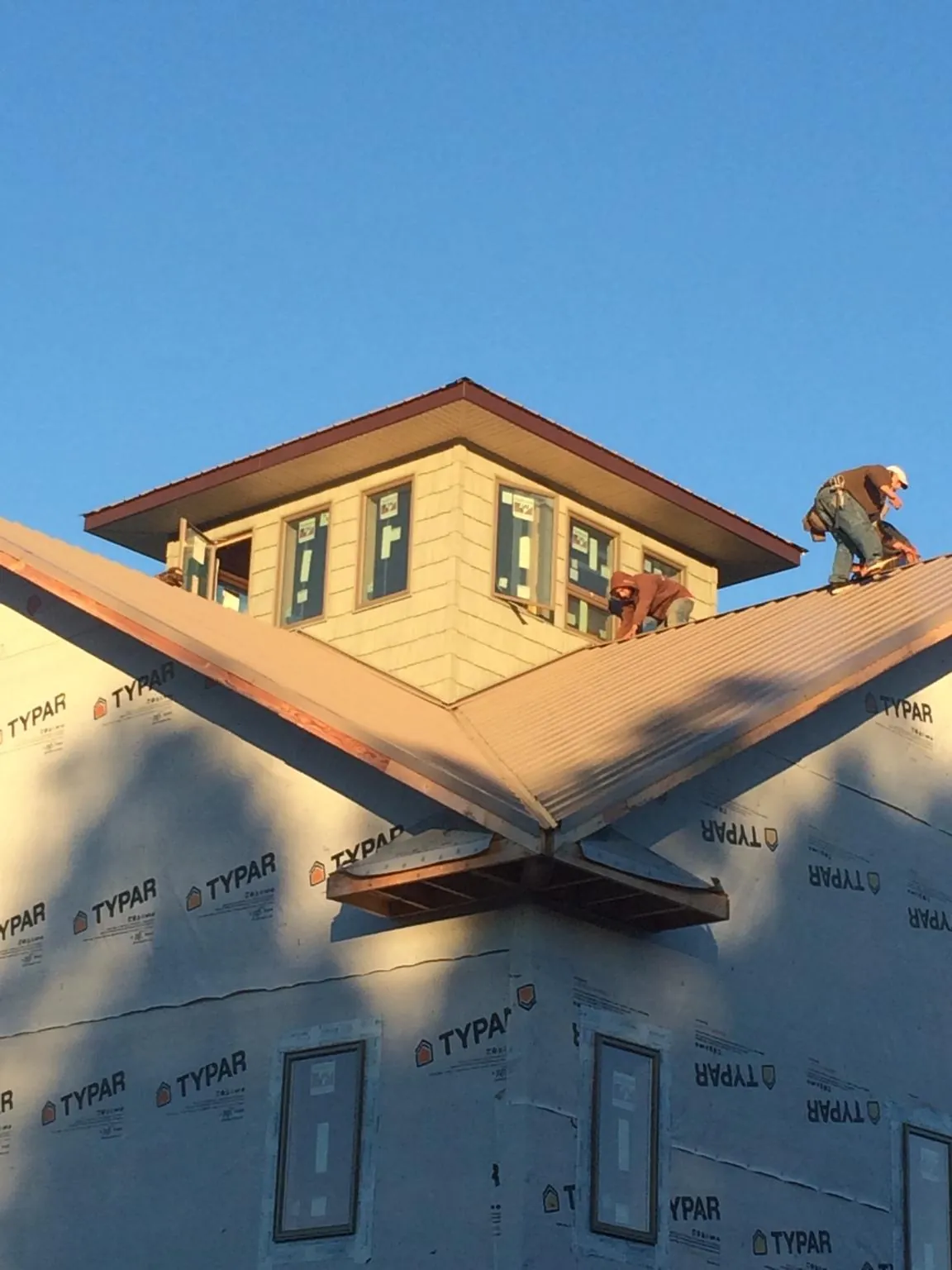 Roofers working around a rooftop cupola on a new metal roof at sunset — Roof Waterproofing in Duvall by Roofing Brothers